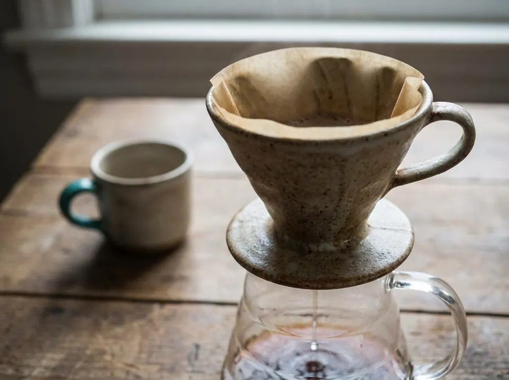 A pour-over coffee dripper filtering liquid through a paper filter, illustrating a selective barrier