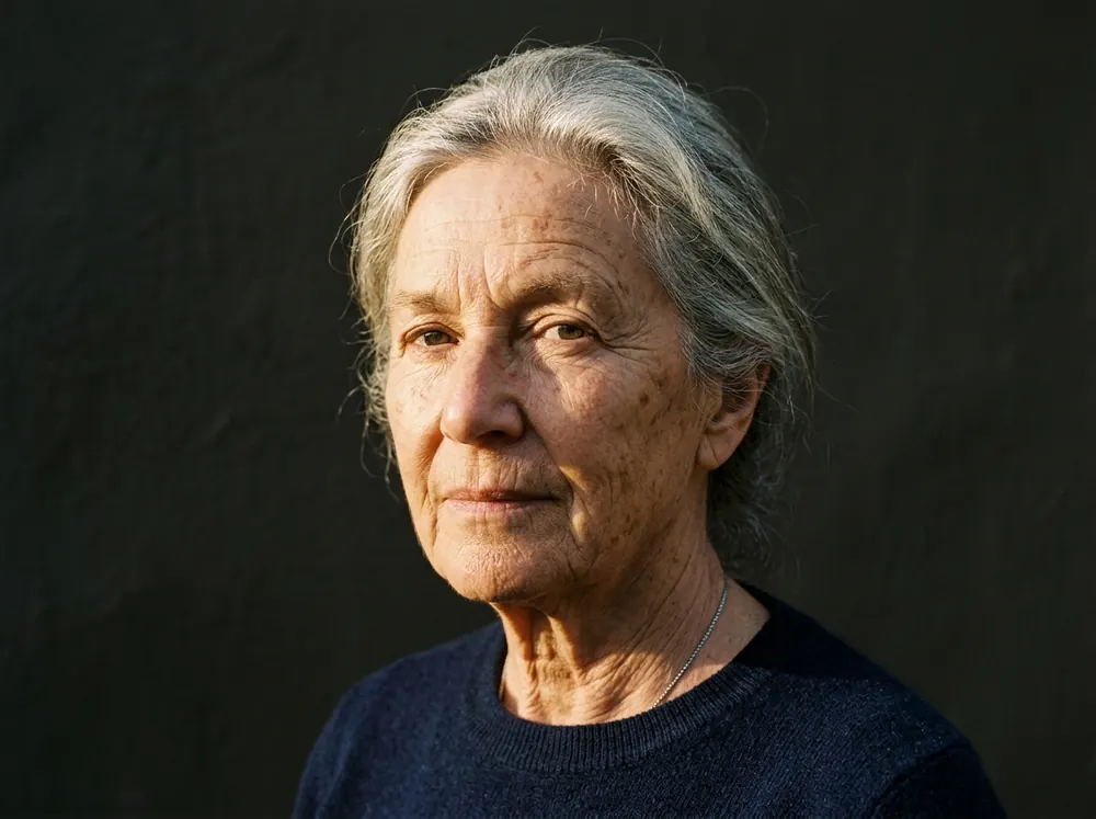 An older woman's face in hard low-angle sunlight, fine lines and skin texture clearly visible across her cheek.